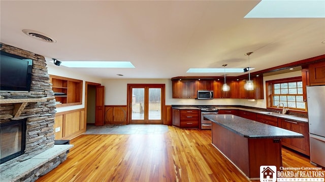 kitchen featuring light wood-type flooring, a skylight, appliances with stainless steel finishes, and plenty of natural light