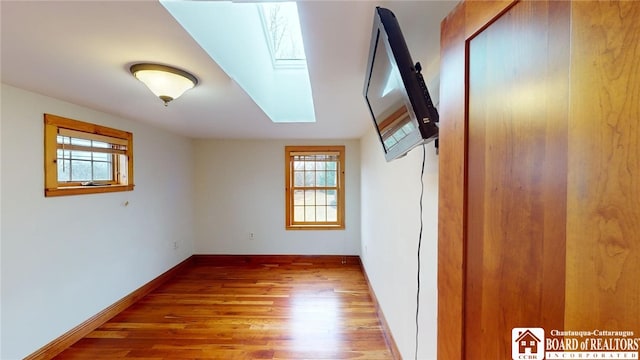 additional living space featuring a skylight and hardwood / wood-style flooring