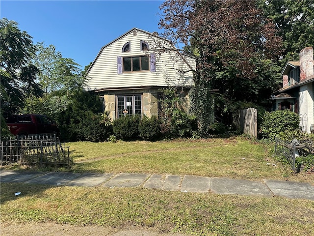 view of front of house featuring a front yard, fence, and a gambrel roof