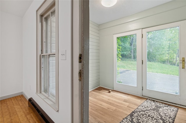 doorway to outside with light hardwood / wood-style floors and wood walls