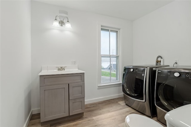 washroom with sink, light wood-type flooring, and independent washer and dryer