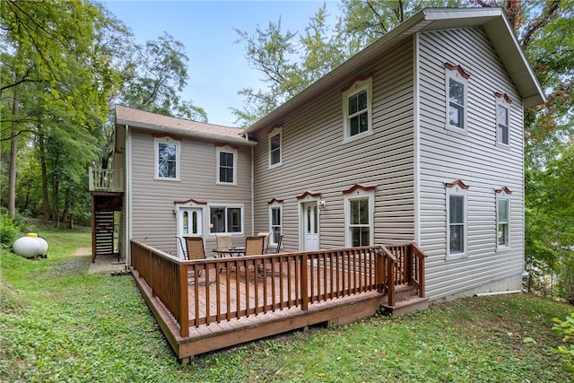 rear view of house featuring a wooden deck and a lawn