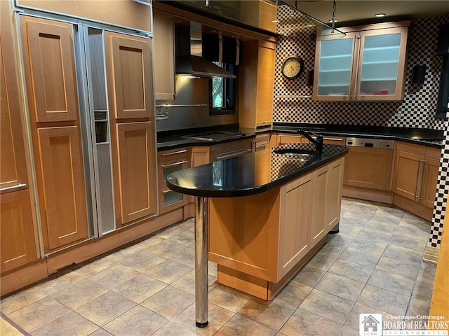 kitchen featuring an island with sink, backsplash, wall chimney exhaust hood, decorative light fixtures, and sink