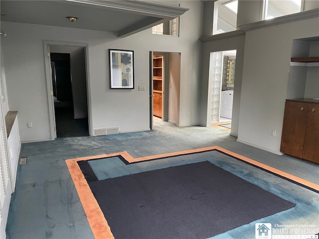 interior space with a towering ceiling, washer / clothes dryer, and carpet floors