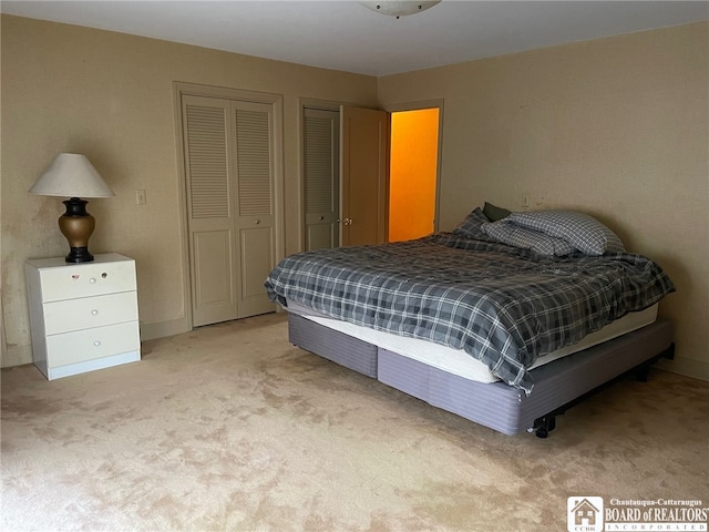 bedroom with light colored carpet and multiple closets