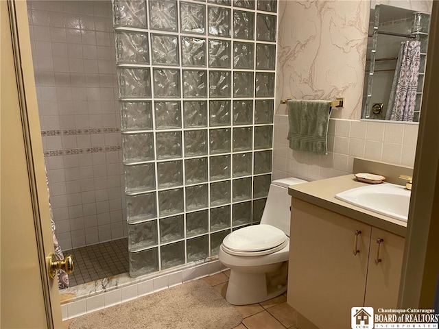 bathroom featuring a tile shower, tile patterned floors, vanity, and toilet