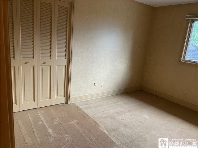 unfurnished bedroom featuring light carpet and a closet