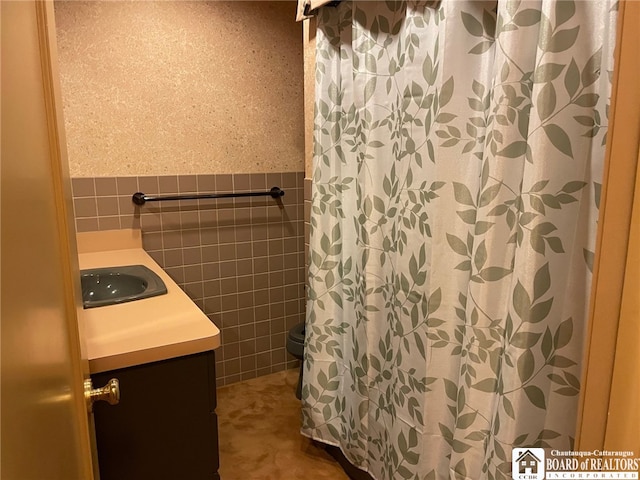 bathroom with tile walls, walk in shower, vanity, and toilet