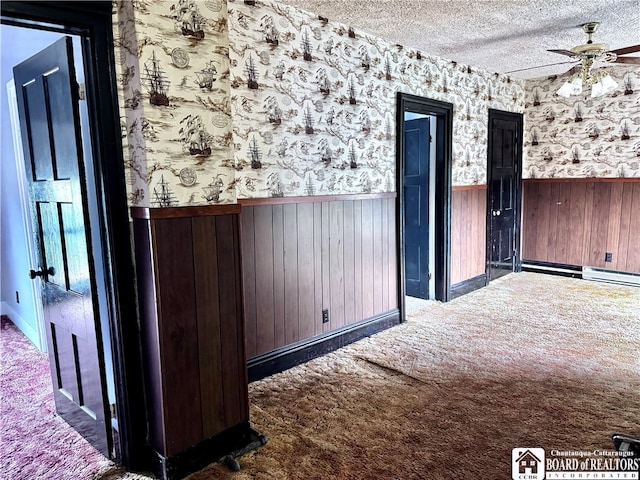 interior space featuring a textured ceiling, wooden walls, and carpet flooring