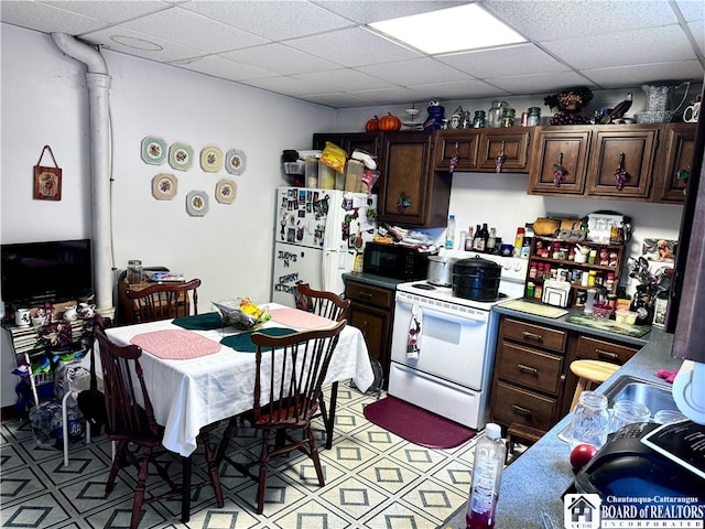 kitchen featuring white appliances, dark brown cabinetry, and a paneled ceiling