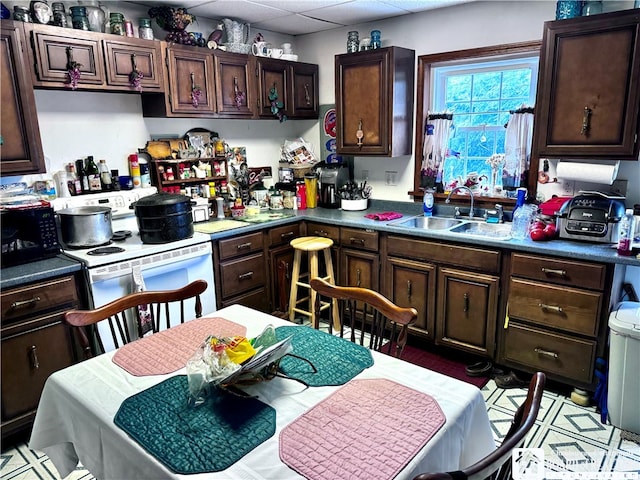 kitchen with a paneled ceiling, dark brown cabinets, white electric range, and sink