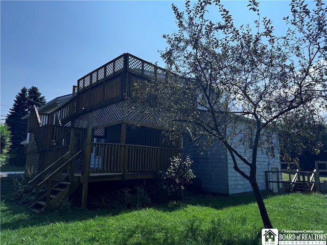 rear view of property with a wooden deck and a lawn