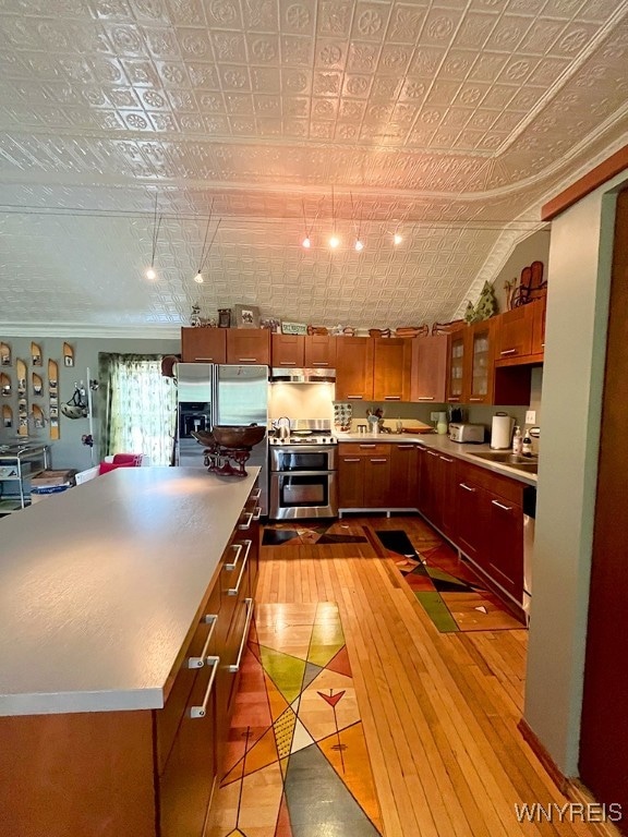 kitchen featuring lofted ceiling, sink, stainless steel appliances, light wood-type flooring, and crown molding