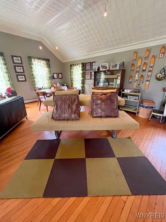 living room with ornamental molding, light hardwood / wood-style floors, vaulted ceiling, and a baseboard radiator