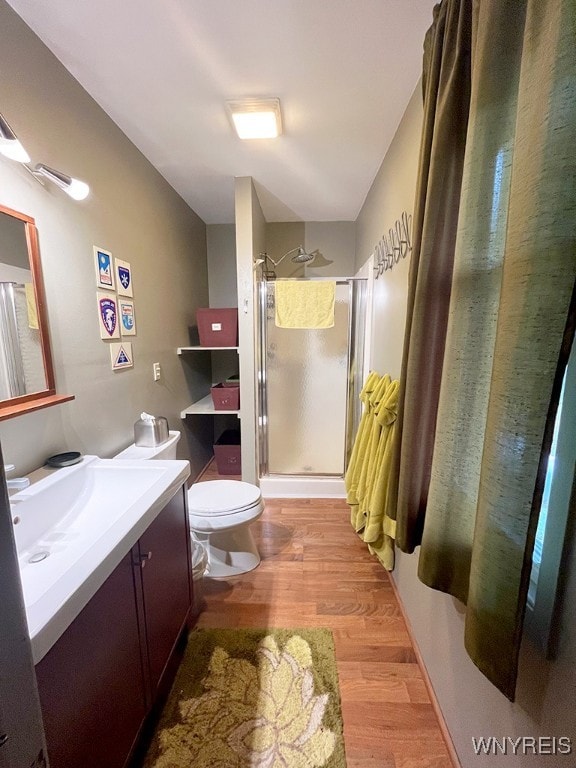 bathroom featuring wood-type flooring, vanity, toilet, and an enclosed shower