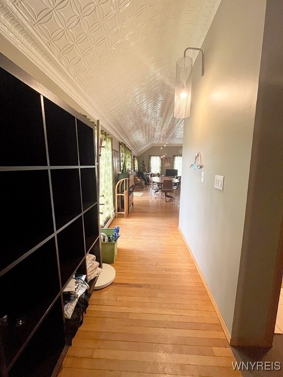 hallway with wood-type flooring and vaulted ceiling