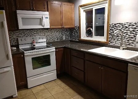 kitchen with decorative backsplash, white appliances, light tile patterned flooring, and sink