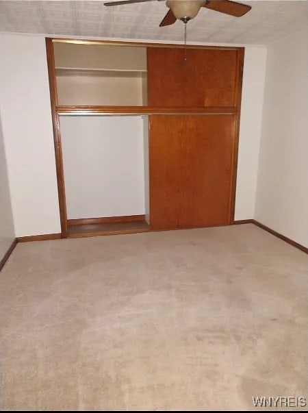 unfurnished bedroom featuring ceiling fan, light colored carpet, and a closet