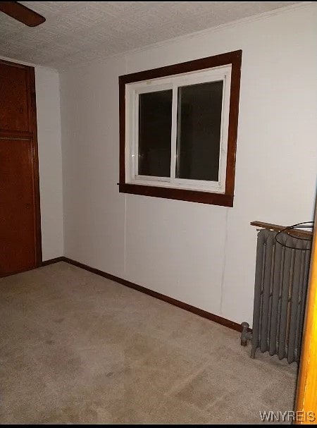 unfurnished room with radiator, a textured ceiling, light colored carpet, and ceiling fan