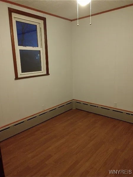 empty room with wood-type flooring and ornamental molding