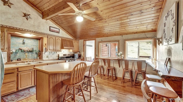 kitchen with beamed ceiling, light hardwood / wood-style floors, a kitchen island, and sink