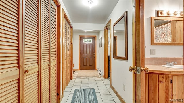 hallway with sink, light tile patterned flooring, and a baseboard radiator