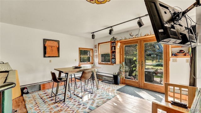 dining area featuring a baseboard heating unit, track lighting, and light wood-type flooring