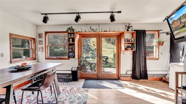 interior space featuring light hardwood / wood-style flooring, rail lighting, and a baseboard heating unit