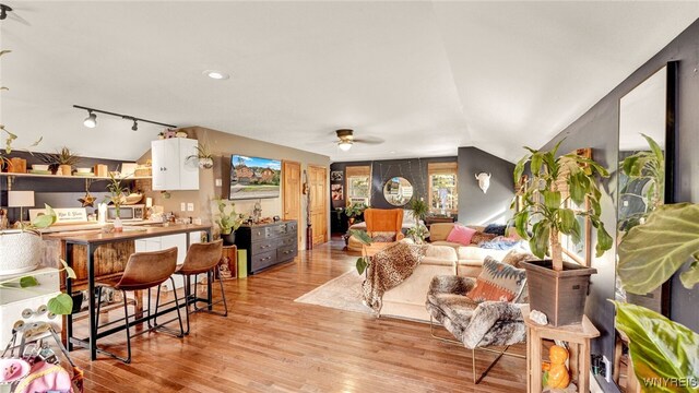 living room featuring ceiling fan, track lighting, light hardwood / wood-style floors, and vaulted ceiling