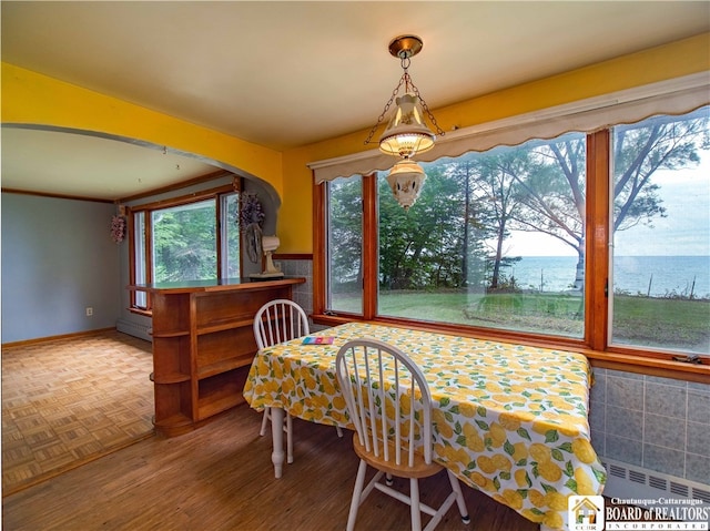 dining area with wood-type flooring, baseboard heating, and a water view