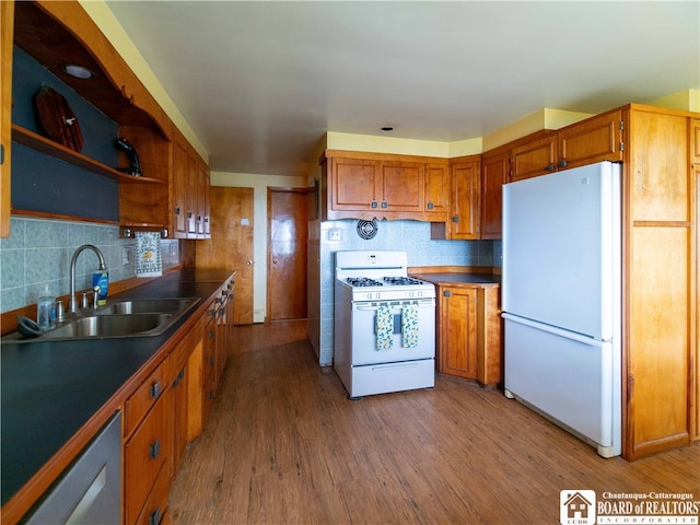 kitchen with wood-type flooring, sink, white appliances, and decorative backsplash