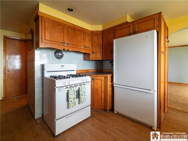 kitchen with decorative backsplash, white appliances, and light hardwood / wood-style floors