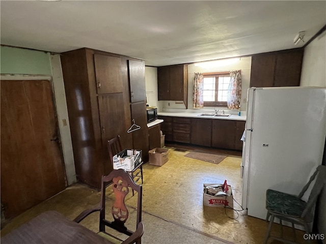 kitchen featuring white fridge, sink, and dark brown cabinets