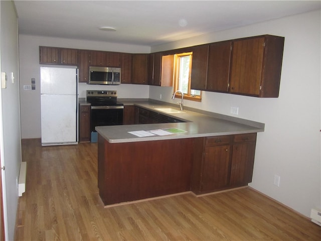 kitchen with sink, kitchen peninsula, dark brown cabinets, light hardwood / wood-style flooring, and appliances with stainless steel finishes