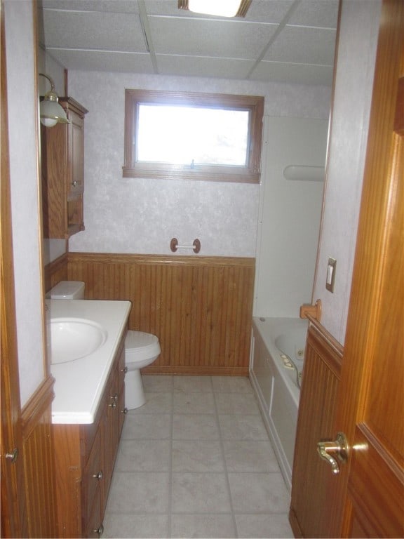 bathroom with wooden walls, vanity, a drop ceiling, and toilet