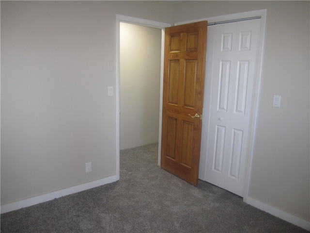 unfurnished bedroom featuring dark carpet and a closet