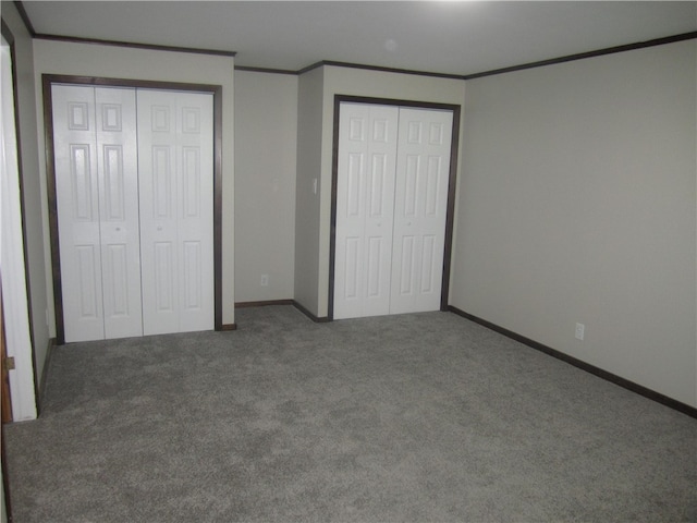 unfurnished bedroom with carpet floors, multiple closets, and ornamental molding