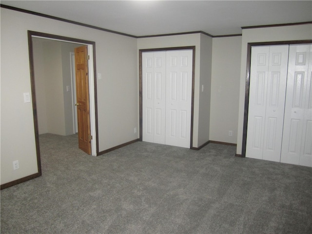 unfurnished bedroom featuring dark carpet, multiple closets, and ornamental molding