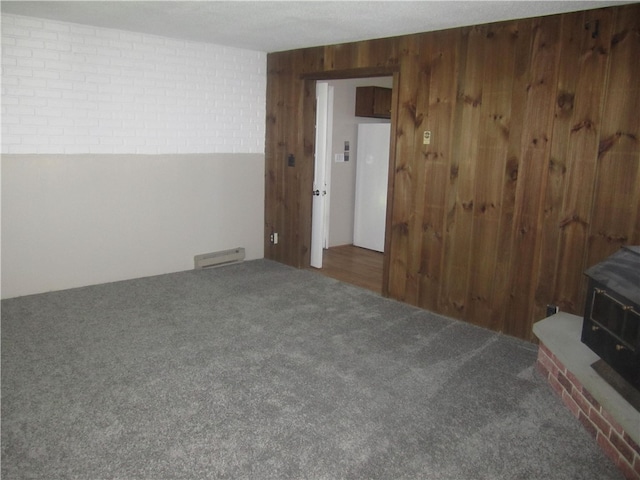 carpeted spare room with a textured ceiling and wooden walls