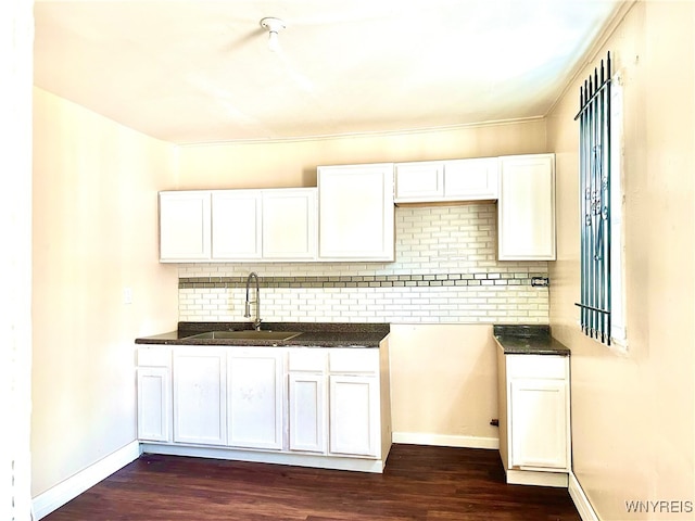 kitchen featuring decorative backsplash, white cabinets, dark wood-type flooring, and sink