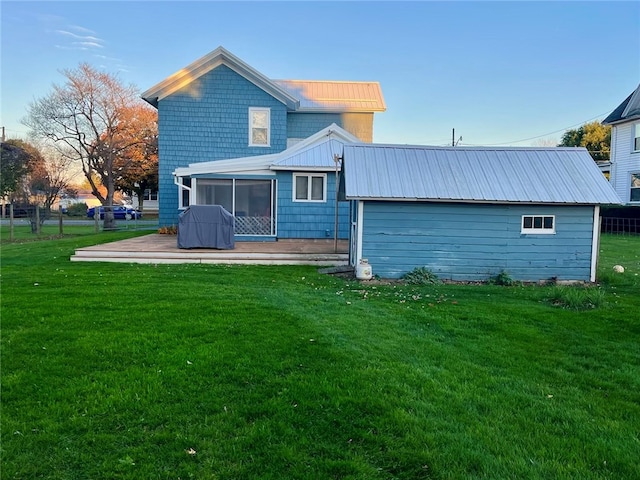 back house at dusk with a patio, a sunroom, and a yard