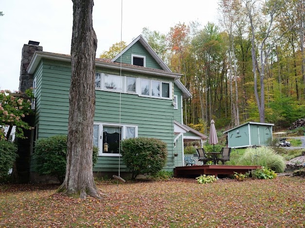 back of property with a wooden deck and a shed