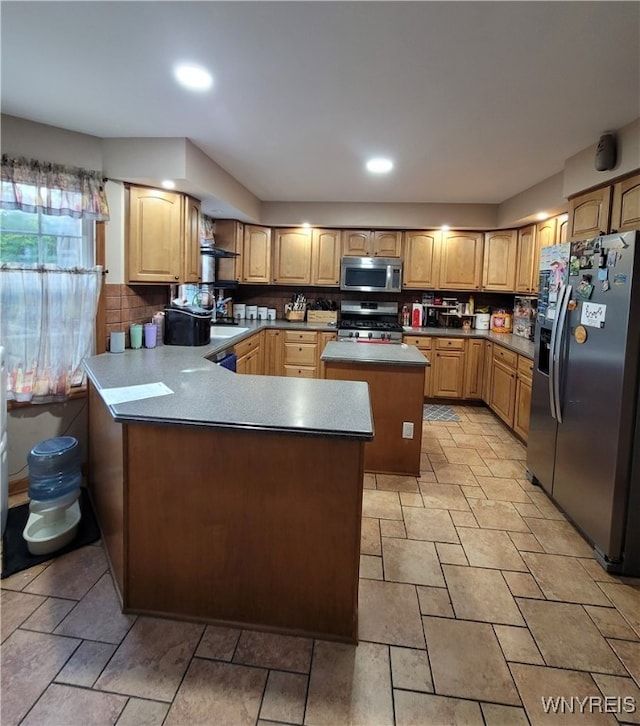 kitchen featuring appliances with stainless steel finishes, sink, tasteful backsplash, and a center island