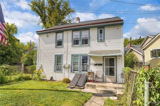 rear view of property featuring a lawn