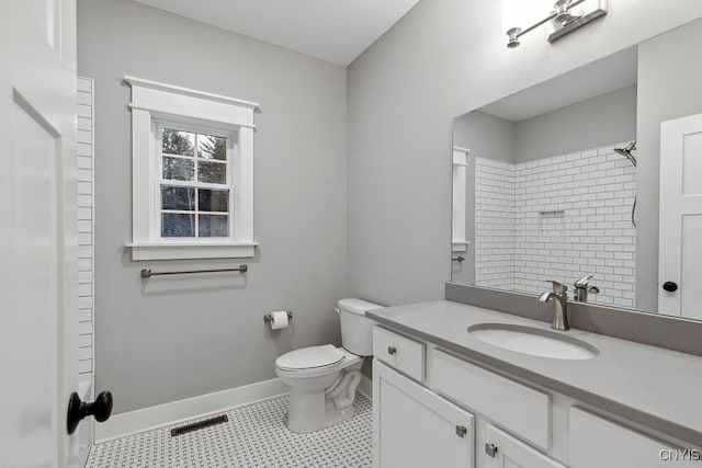 bathroom featuring tile patterned flooring, vanity, toilet, and tiled shower