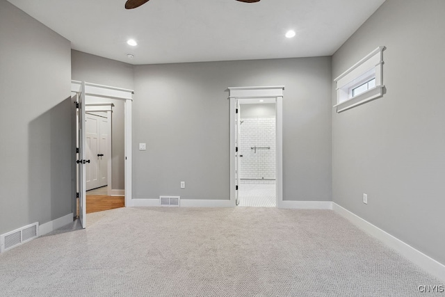 unfurnished bedroom featuring ceiling fan, light colored carpet, and connected bathroom