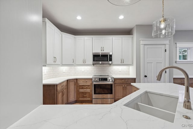 kitchen with pendant lighting, stainless steel appliances, sink, and white cabinetry