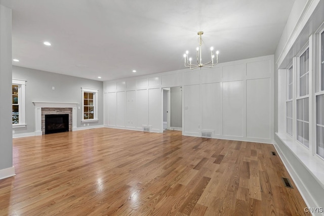 unfurnished living room with light hardwood / wood-style flooring, a chandelier, and a fireplace