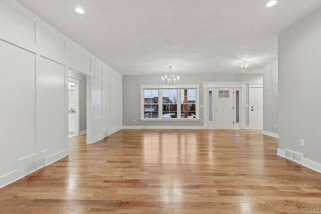 unfurnished living room featuring light hardwood / wood-style floors and a notable chandelier