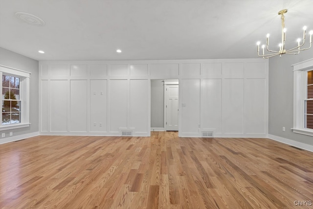 unfurnished living room featuring light hardwood / wood-style flooring and an inviting chandelier